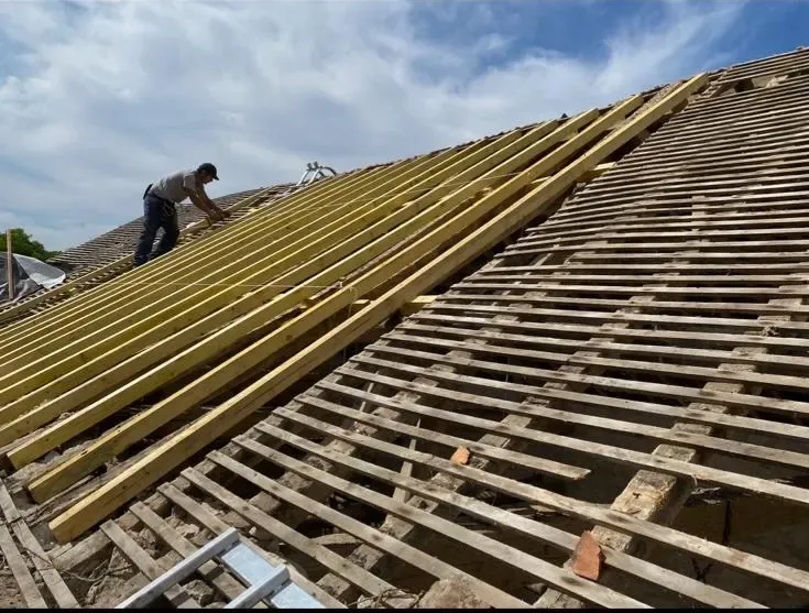 Charpentier SDR Habitat 44 posant les liteaux sur une charpente bois neuve à La Baule