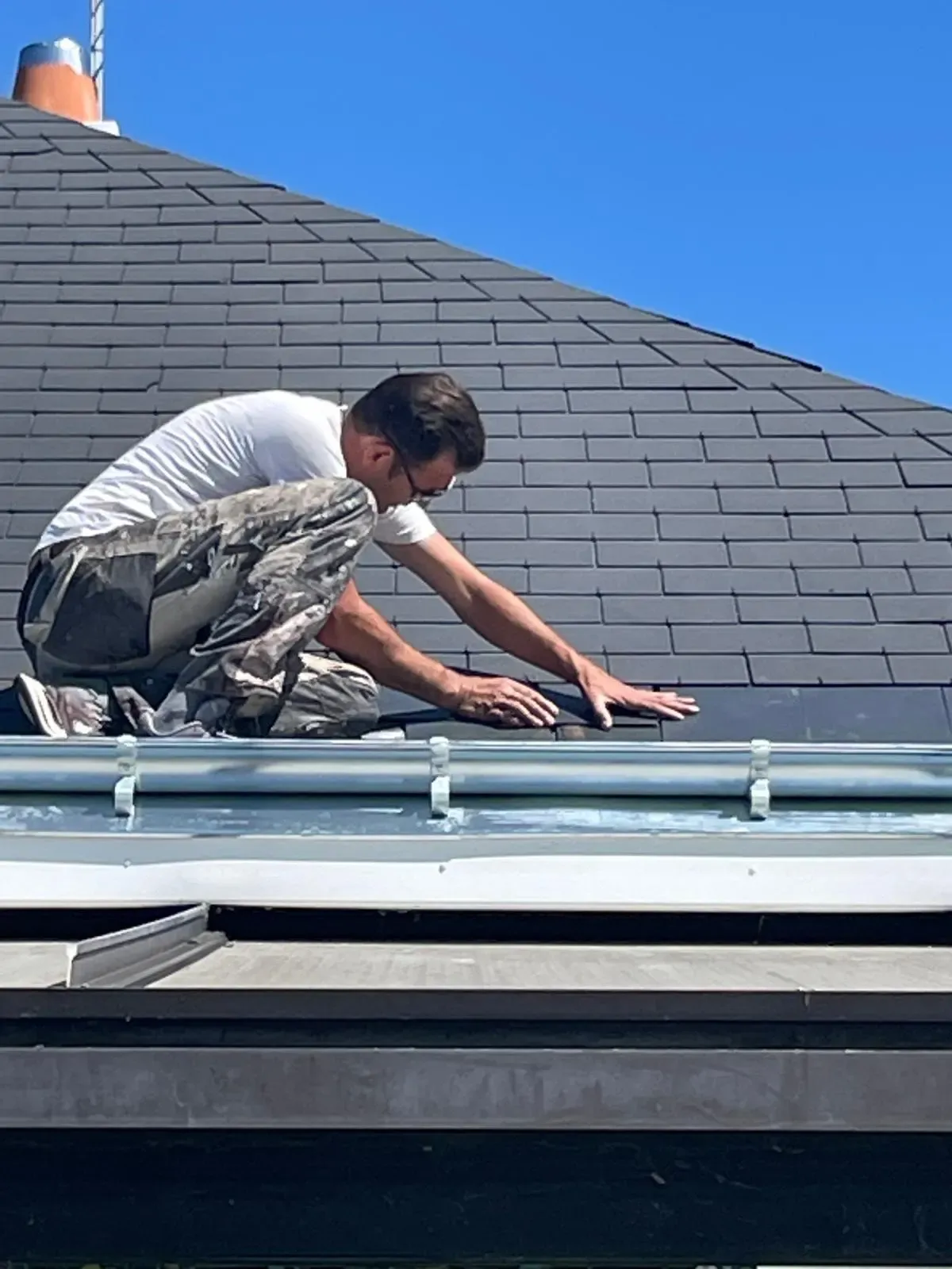 Couvreur SDR Habitat 44 posant des ardoises et une noue en zinc sur une toiture à La Baule