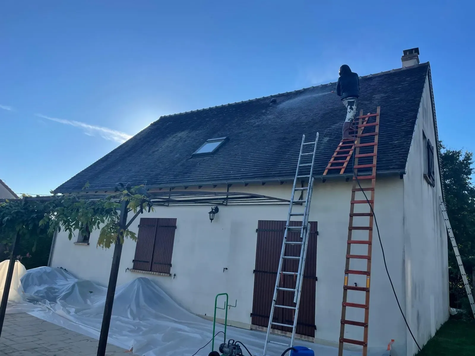 Couvreur SDR Habitat 44 en train de démousser une toiture en tuiles à La Baule